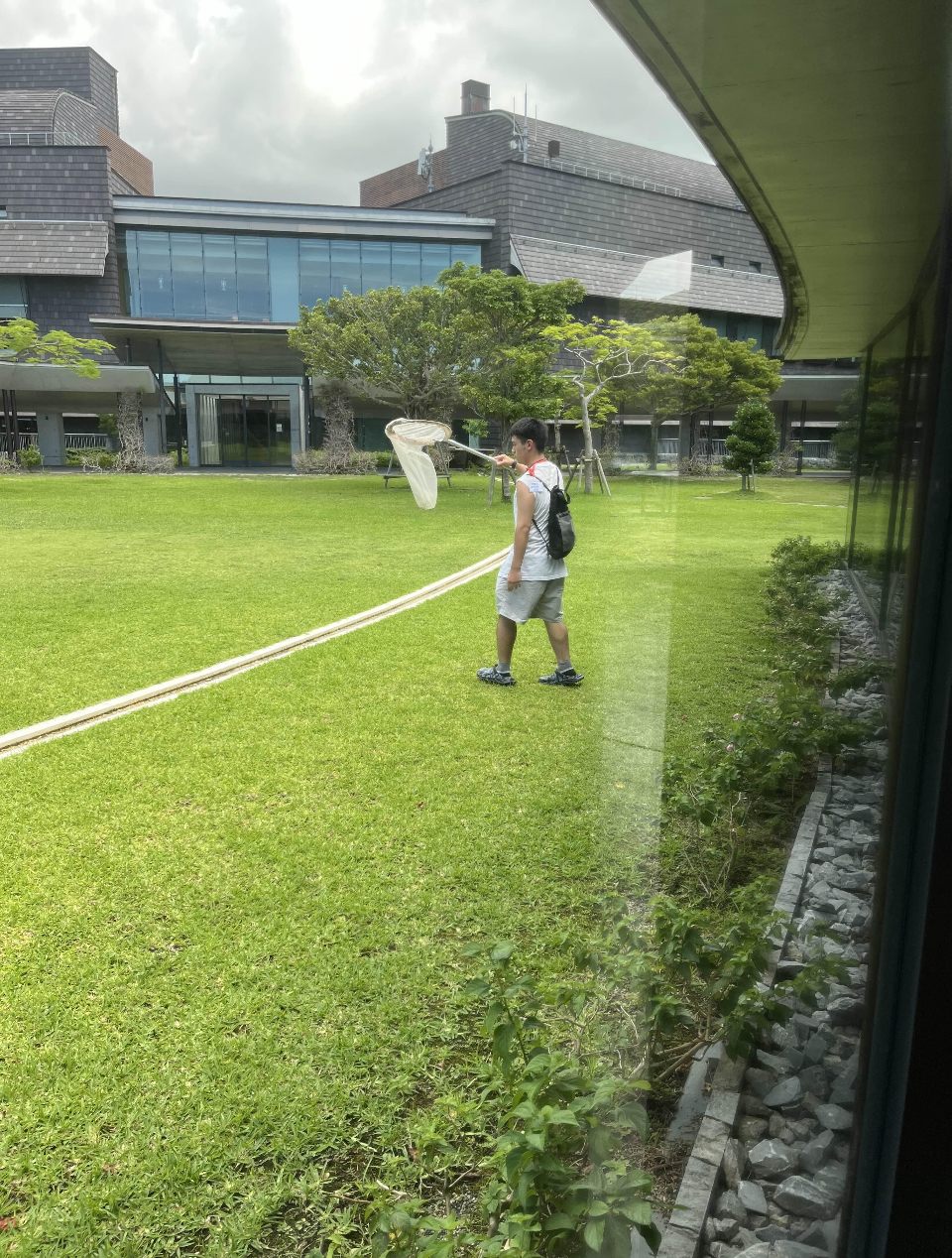 芝生の上で捕虫網を構える岩﨑惣大