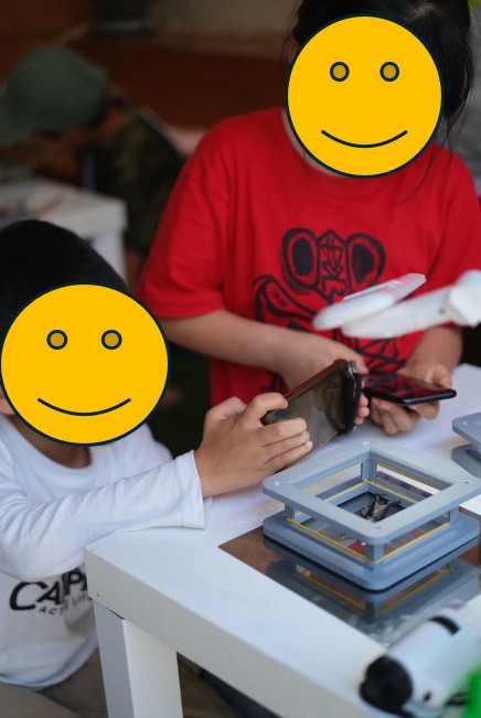子どもたちがスマホでI-BOXの中の昆虫を撮影している様子